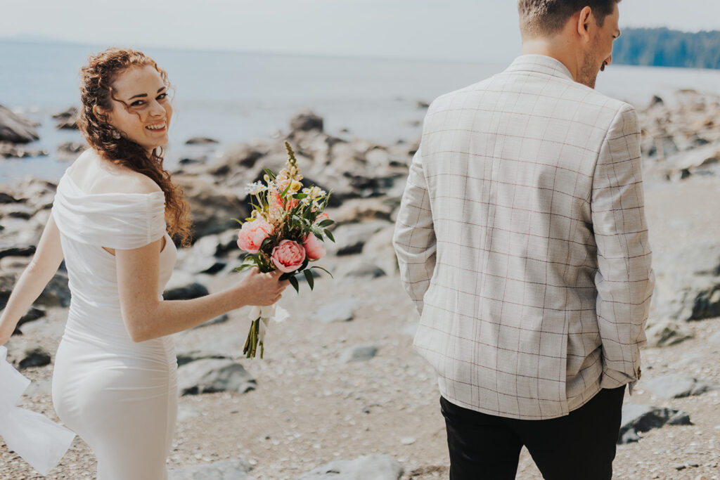 A couple walks along the beach in Jordan River, BC on their elopement day.